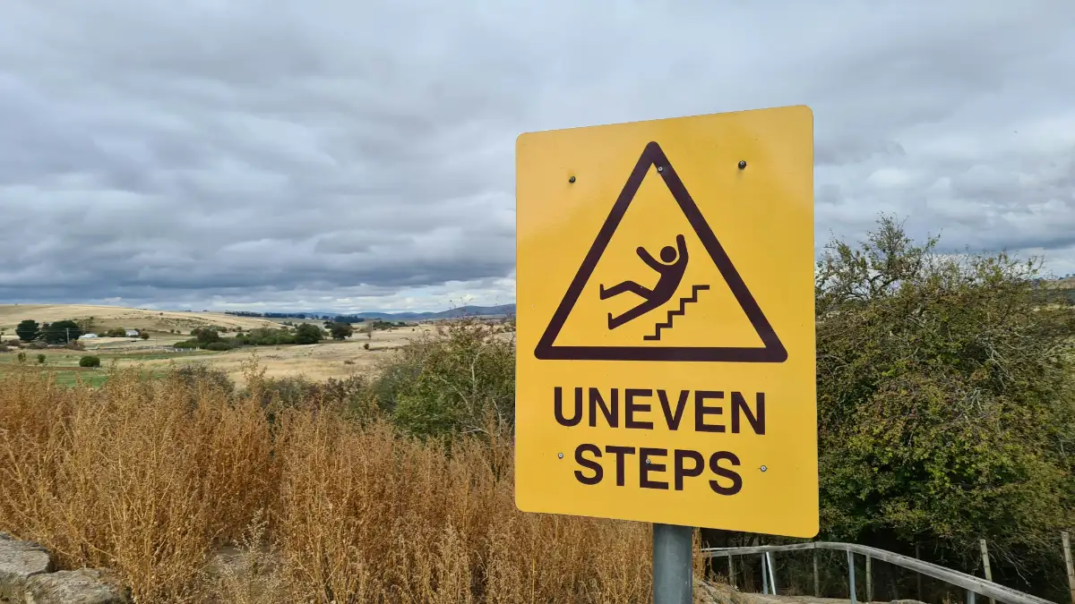 Yellow sign that says uneven steps on it